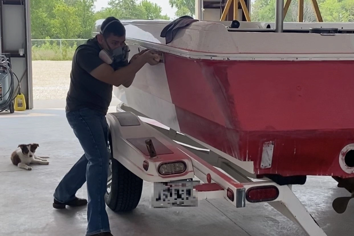 Jon Turner doing fiberglass boat repair work on a red boat